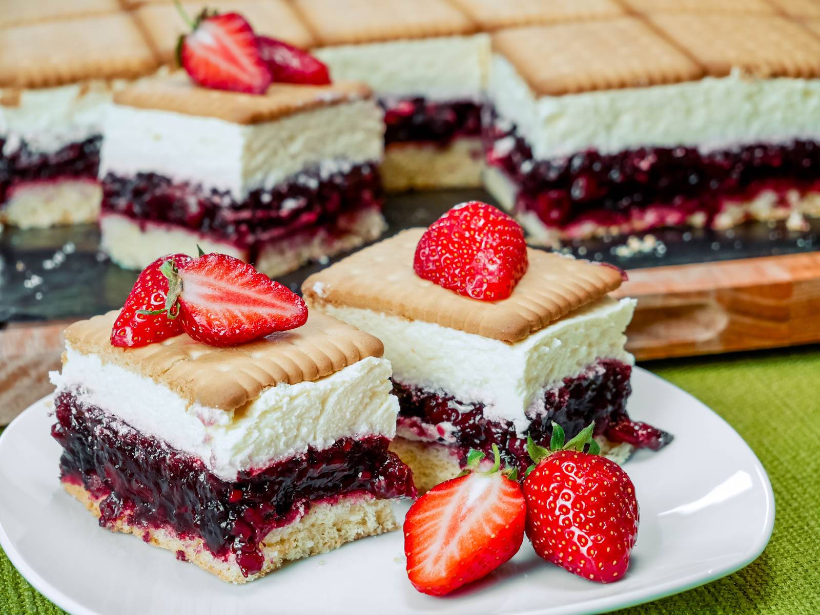 Schichten von Butterkekskuchen mit Roter Grütze, dekoriert mit frischen Erdbeeren, auf einem Teller.