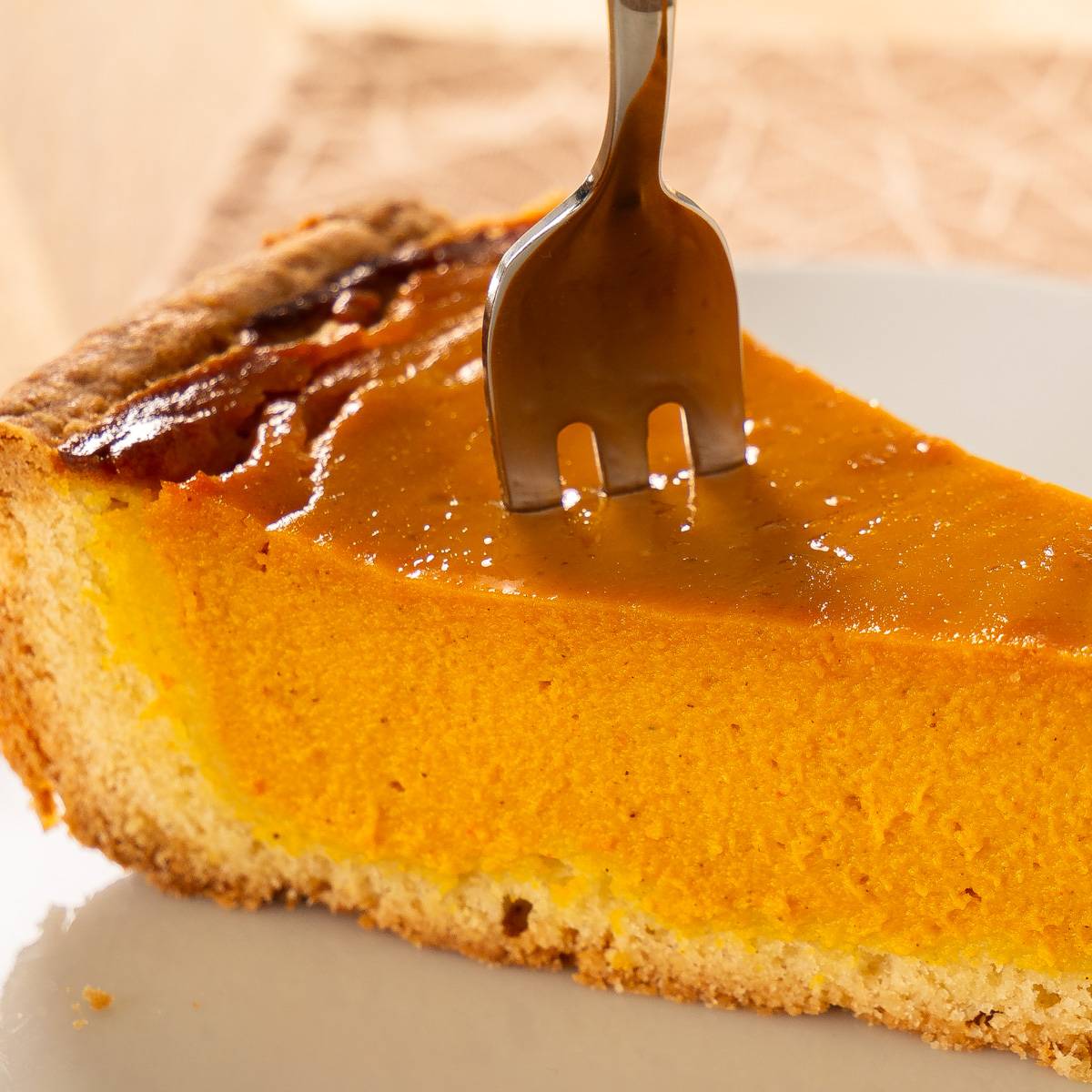 Leckeres Pumpkin Pie Rezept – Der amerikanische Klassiker Ein Stück Pumpkin Pie, auf das eine Gabel in die cremige Füllung gedrückt wird.