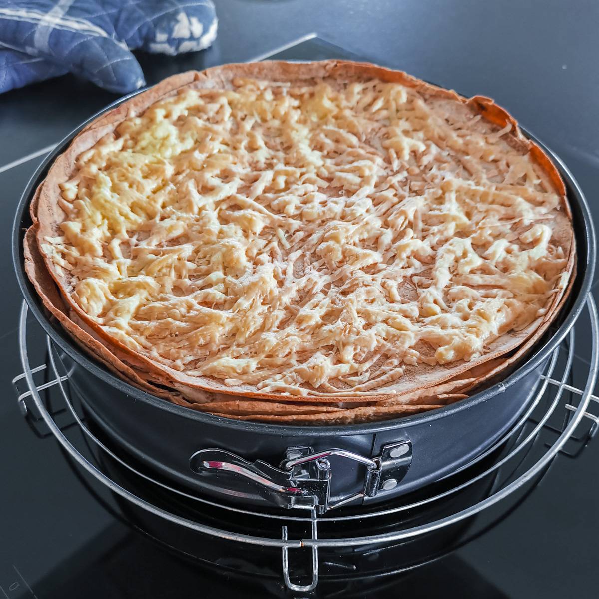 Mexikanische Tortilla Lasagne – Der perfekte Wrap Auflauf für alle Tex-Mex-Fans! Fertige Mexikanische Tortilla Lasagne in einer Springform, goldbraun überbacken und auf einem Abkühlgitter präsentiert.