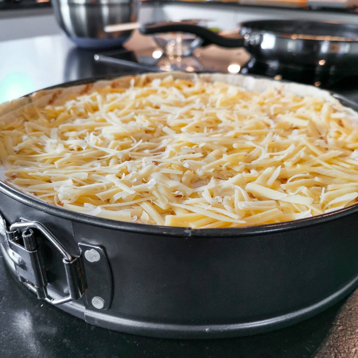 Mexikanische Tortilla Lasagne – Der perfekte Wrap Auflauf für alle Tex-Mex-Fans! Die fertig geschichtete Mexikanische Tortilla Lasagne wird mit Käse bestreut, bevor sie in den Ofen kommt.